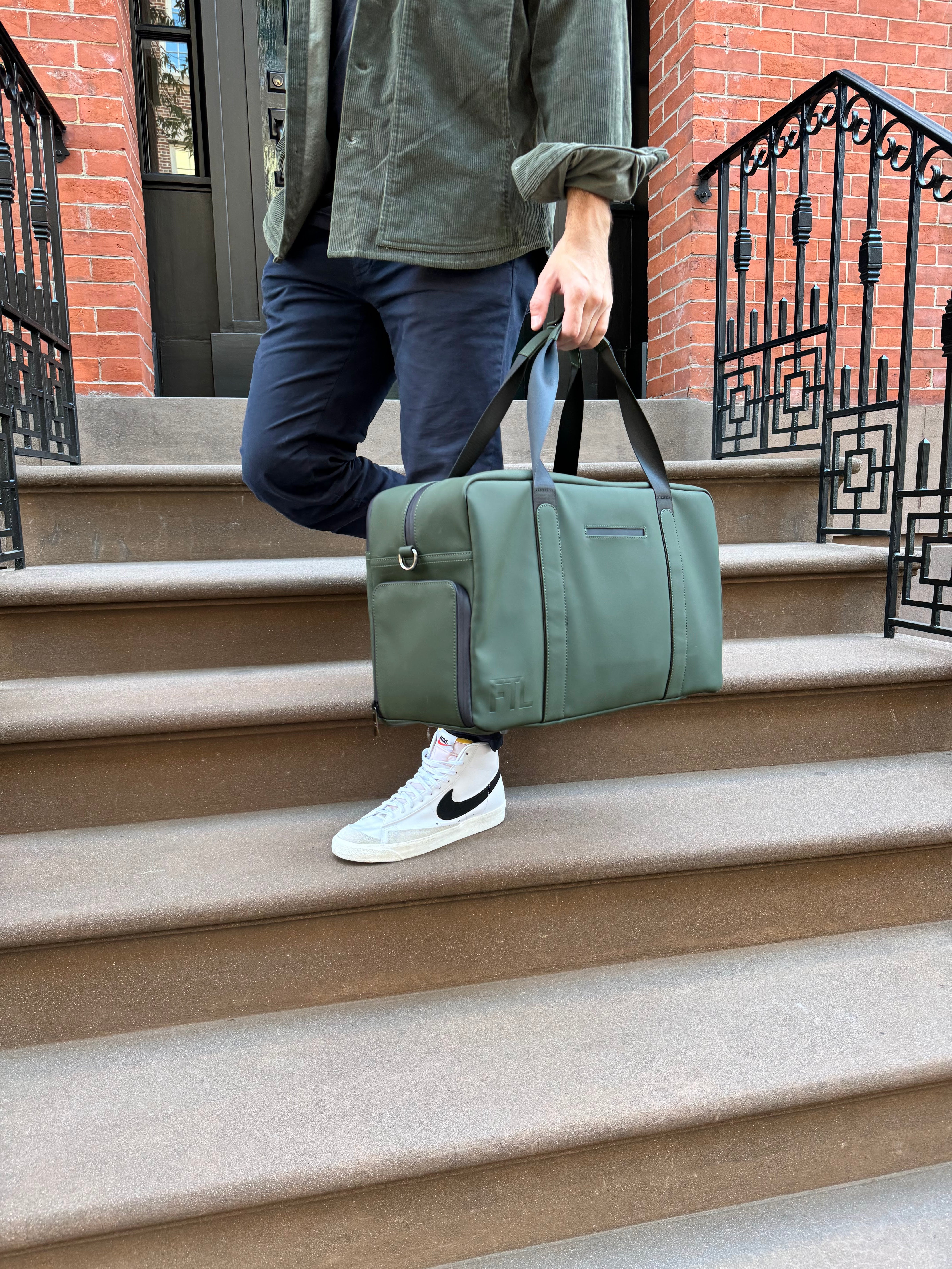 Men's duffle bag for the gym in olive green, shown in use with casual urban outfit for everyday active lifestyle.